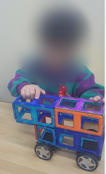 맥포머스 블록으로 버스를 만들어 보는 아이. 얼굴은 모자이크 처리됨